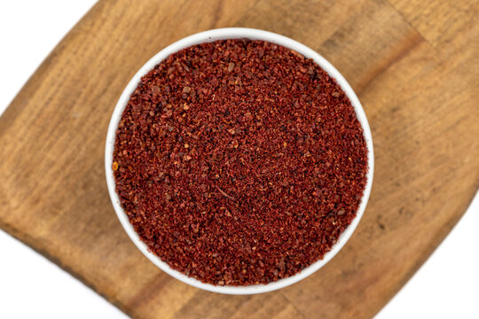 Sumac isolated on white background. Dried ground red Sumac powder spices in wooden bowl. Top view
