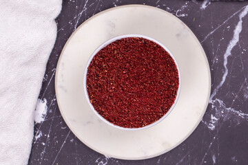Sumac on dark background. Dried ground red Sumac powder spices in wooden bowl. Top view