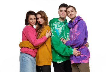 Portrait of four young people, friends, couples in colorful hoodies posing over white background. LGBTQIA supporters. Concept of lgbt community, support, love, human rights, pride month