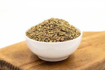 Dried crushed basil isolated on white background. Dried ground basil powder spices in ceramic bowl. Spice concept