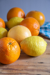 Top view of oranges, lemons and grapefruits on rustic wooden table with cloth, vertical with copy space