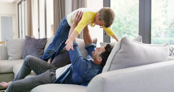 Father, son and playing with fun in living room, love and bonding with happiness at family home. Man tickling boy child on couch, lifting in air and relationship with happy people at house