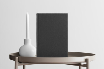 Black book mockup with a candle decoration on the beige table.