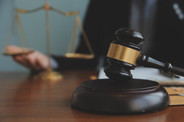 Business and lawyers discussing contract papers with brass scale on desk in office. Law, legal services, advice, justice and law concept picture with film grain effect