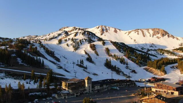 Aerial Cinematic drone early sunrise Spring Mammoth Mountain California ski trails and ski lodge parking lot gondola and chair lift backward movement