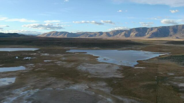 Aerial Cinematic drone Mammoth Lakes California Sierra Nevada  hilltop hot spring field and mountain landscape late after sunset up skier snowboarders soak camp to the forward movement