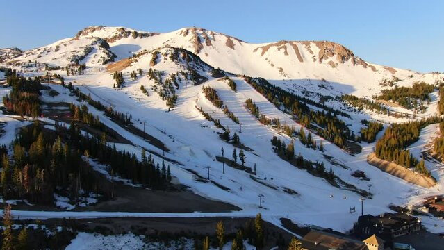 Aerial Cinematic drone early sunrise Spring Mammoth Mountain California ski trails and ski lodge parking lot gondola and chair lift to the right movement