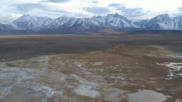 Aerial Cinematic drone Mammoth Lakes California Sierra Nevada  hilltop hot spring field and mountain landscape late after sunset up skier snowboarders soak camp to forward reveal pan up movement
