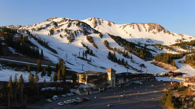 Aerial Cinematic drone early sunrise Spring Mammoth Mountain California ski lodge parking lot gondola and chair lift up movement