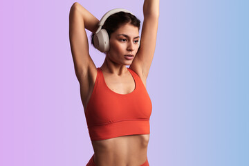 Fototapeta na wymiar Athletic Hispanic lady stretching triceps and listening to song in headphones