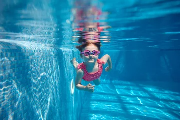 Tapeten Cute little baby girl, toddler in pink swimsuit diving, swimming underwater in swimming pool. Water sports activity. Concept of sport, healthy and active lifestyle, childhood, fun and training © master1305