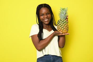Photo of charming happy afro american woman hold pineapple summer fruit isolated on yellow color...