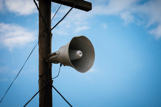 On an old wooden pole, an old megaphone against the blue sky