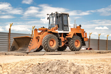 Heavy front loader or bulldozer at the construction site. Construction equipment. Transportation and movement of bulk materials. Rental of construction equipment.