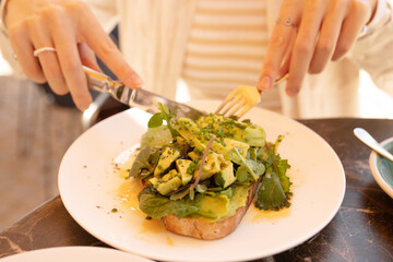 Portrait of a young attractive woman eating salad at cafe table. Horizontal shot.Beautiful young female enjoying a fresh salad at a nice restaurant.