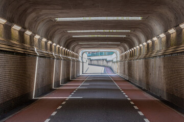 Front view of interior of an empty vehicular tunnel with cycle lanes with a curve in background,...