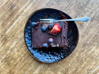 Chocolate cake with blueberries on a wood table outdoors with copy space