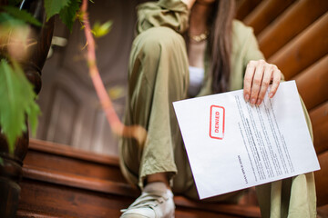 Young brunette long hair girl cries hysterically after being denied a mortgage loan. Depressive sad eviction female millenial holding rejection document copy space banner - obrazy, fototapety, plakaty