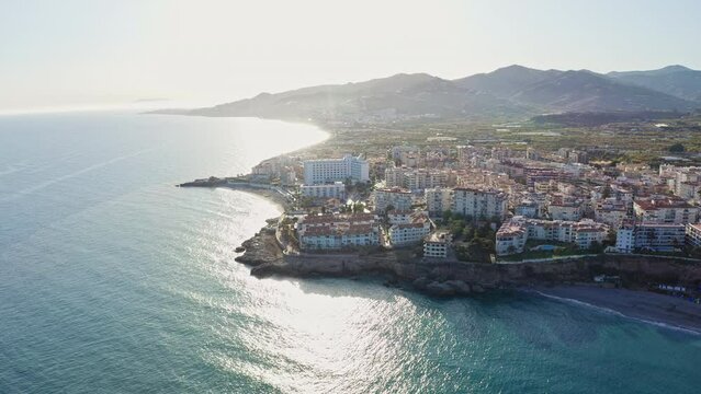 Aerial drone shot of Andalusian coastal town Nerja with seaside cliffs and mountains