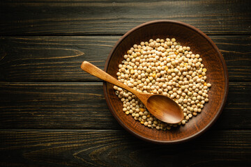 A full plate of dry peas and a spoon on a vintage dark table before cooking. Space for recipe or menu for restaurant or hotel