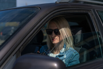 Woman in sunglasses with a camera sits in a car and takes pictures with a professional camera, a...