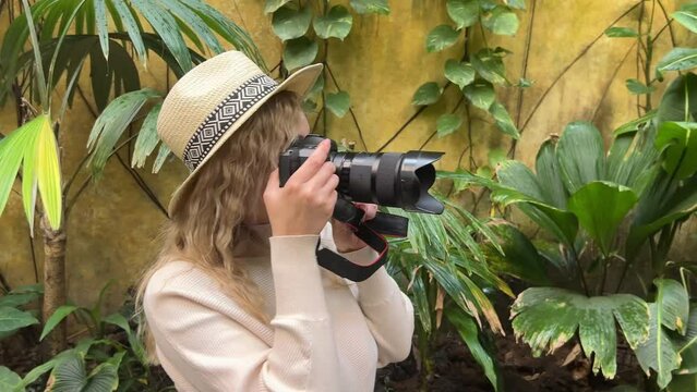 attractive woman taking pictures on a professional camera in a botanical garden