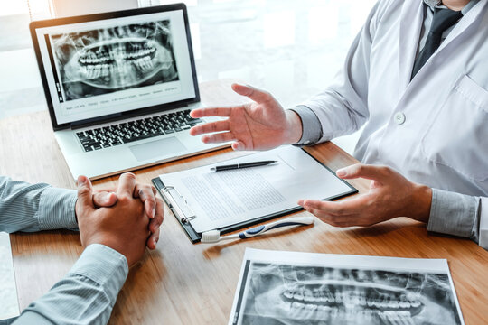 Dentist with male patient presenting discussing dental problems x-ray image film in dental office