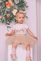 Obraz na płótnie Canvas Baby girl elegant dress. A one-year-old girl in a puffy skirt and a white T-shirt poses against the backdrop of a bright room.