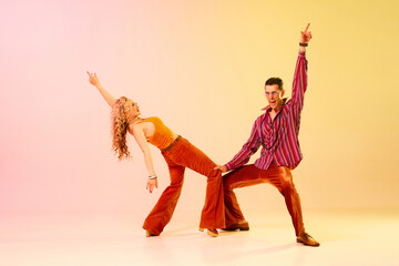 Artistic, expressive couple, man and woman emotionally dancing disco dance against gradient pink...