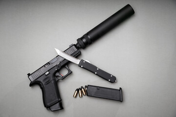 A pistol with a silencer and a folding knife.