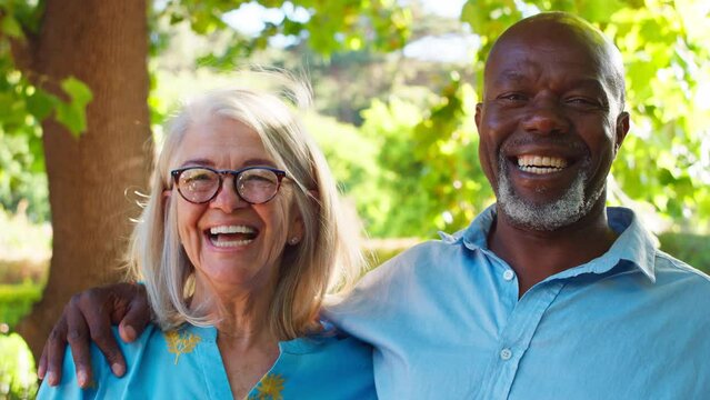 Portrait of happy and loving multi-racial senior couple outside in park, garden or countryside - shot in slow motion
