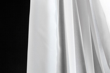 Folds of white transparent tulle textile on a white background.