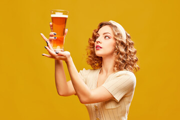 Young redhead girl, Oktoberfest waitress wearing vintage dress holding beer glass over yellow...