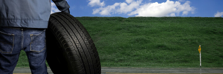 Banner a technician holds a wheel of tire and faces the hills and sky, showing care throughout the journey and all road conditions.