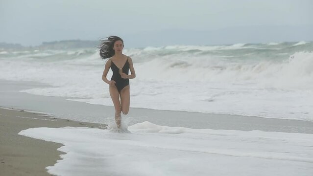 girl runs along the beach during a storm. big noisy ocean waves. atmospheric view. Tropical beach