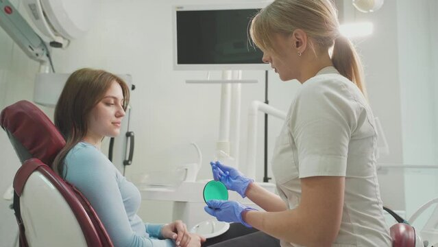 The dentist consults the patient and shows the woman Invisalign braces, transparent plastic removable aligners. Dentistry, dental clinic, orthodontics.