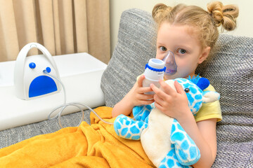 The child breathes with an inhaler together with a toy. Treatment and prevention of childhood...