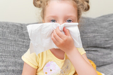The child has a cold. He wipes his nose with a tissue. Strong runny nose.