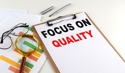FOCUS ON QUALITY text on clipboard with chart on white background, business concept