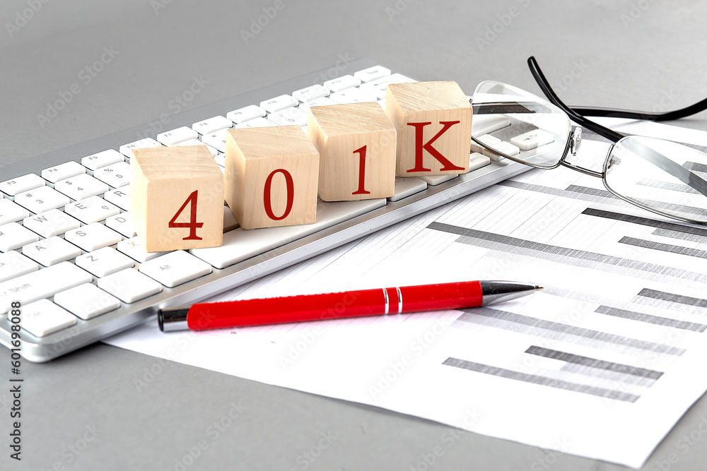 Poster 401k written on a wooden cube on the keyboard with chart on grey background