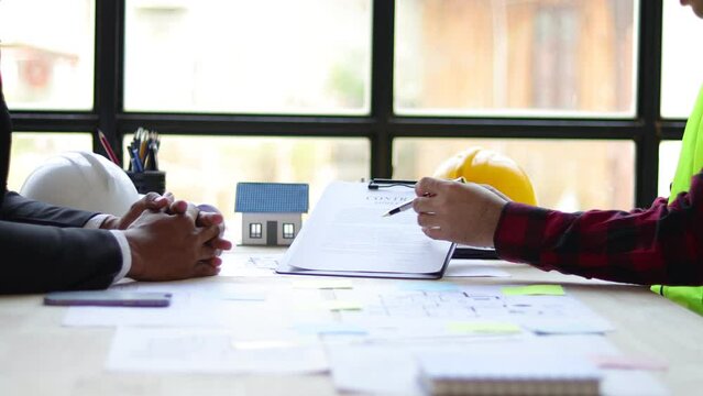 Real estate businessmen discuss with contractor architects to sign contracts for joint construction projects.