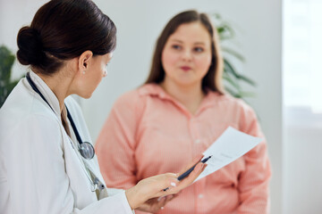A female nutritionist talking with a female overweight patient about her general health condition.
