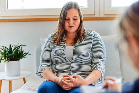 A shy overweight woman on a consulting with a psychotherapist, feeling sad.