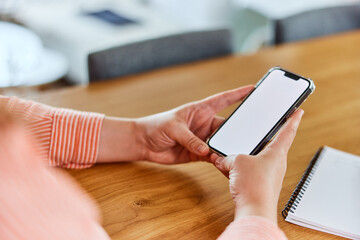 A close-up of a woman using a mobile phone with a blank white screen.