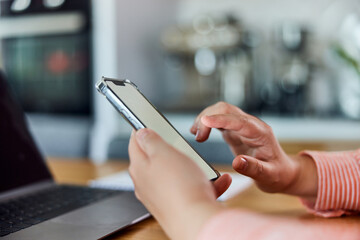 Side view of a woman using a smartphone with blank white screen, indoors.