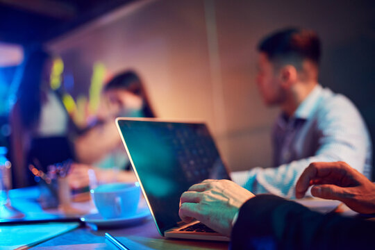 Close-up of male hands typing on laptop. Employees attending business meeting, conference. Blurred background with people. Business, teamwork, company development, career, success, innovations concept