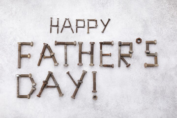 Happy fathers day greeting lettering text from vintage screws top view on white stone background.