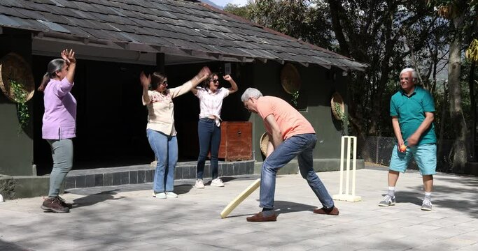 Family members playing cricket in the back yard.