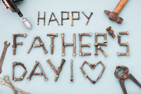Happy fathers day greeting card with tools and lettering text from vintage screws top view on blue background.