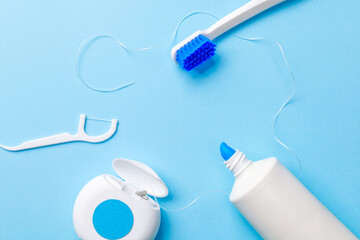Frame of dental floss, a white toothbrush and toothpaste on a blue background